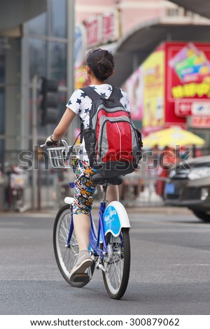 BEIJING-JULY 27, 2015. Young girl rides a public share bicycle. Bicycle sharing allow to hire on a very short term basis, it is a very popular transport mode among commuters in major Chinese cities.