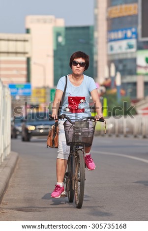 BEIJING-JULY 24, 2015. Fashionable woman on a bicycle. Although the fast multiplication of cars in China the bicycle remains the biggest means of individual mobility for hundreds of millions Chinese.