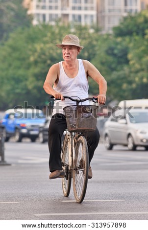 BEIJING-JULY 27, 2015. Male senior on a rusty bicycle. China\'s elderly population (60 years or older) is currently about 128 million, which means one in every ten people, the largest in the world.