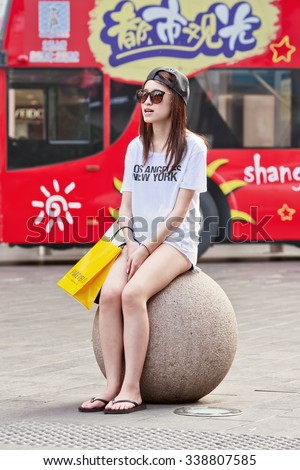 SHANGHAI-JUNE 5, 2014. Pale skin girl on concrete ball. In contrast with the West a white skin is a beauty ideal in China since ancient times. A tanned skin will be associated with low class workers.