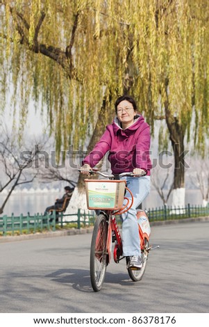 HANGZHOU, CHINA – DEC. 23. Woman cycles at Hangzhou West Lake. It is one of China’s top tourist sites. Since 2011 West Lake is also a UNESCO World Heritage Site. Hangzhou, Dec. 23, 2009