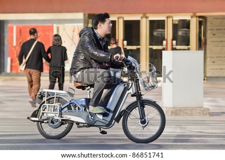 BEIJING - OCT. 17, 2011. Man on electric bicycle in Beijing. Currently, many Beijing residents buy battery-powered bicycles to avoid wasting time on congested streets. Beijing, October 17, 2011.