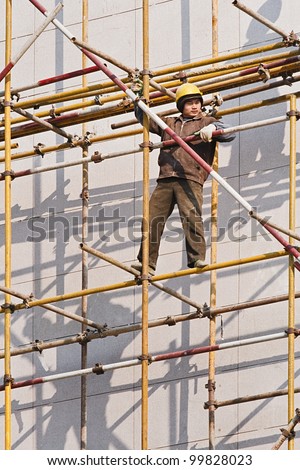 WEIHAI-CHINA-DEC. 4, 2006. Chinese worker on scaffold on Dec. 4, 2006 in Weihai. China\'s 200 million migrant workers travel from rural areas to big cities to work in factories or construction sites.