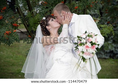 Wedding kiss. The groom kisses the bride (wife) on the ash branches background.