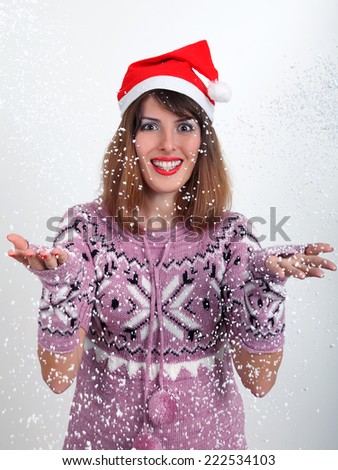 Winter is a magic time! The smiling girl in Santa\'s hat catches snowflakes which fall from the sky on her.