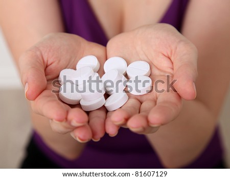 Taking pills Close-up of a white pill in woman\'s fingers.
