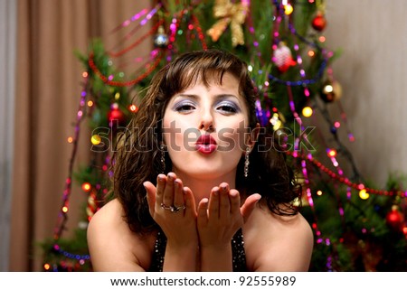 Let your dreams come true!The portrait of the girl blowing kiss on the christmas tree background.