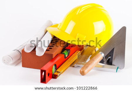 brick, yellow hard hat, tools and construction plans on white background