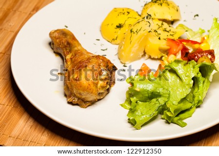 Roast chicken on plate with potatoes and salad