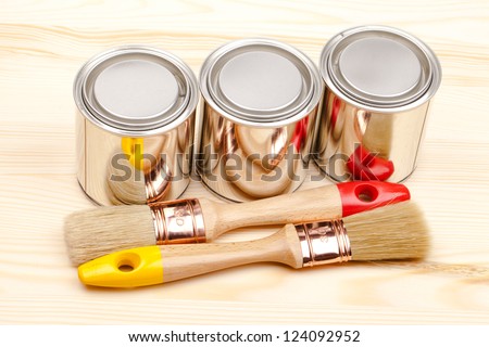 Cans of paint with paintbrushes on wooden table