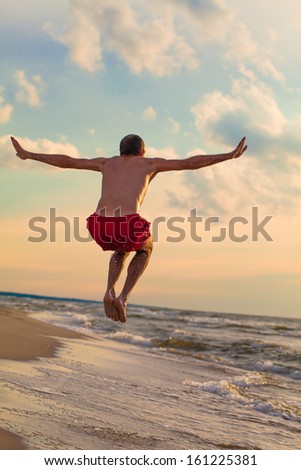 Happy man jumping on the beach