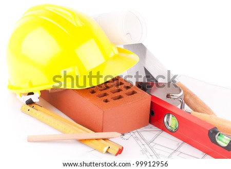 brick, yellow hard hat, tools and construction plans  isolated on white background