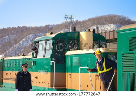 HOKKAIDO, JAPAN-1 FEB. 2013: Train Conductor in Hokkaido, Japan on Feb, 1, 2013, a snow day. Unidentified Japanese train conductor observes passenger before giving a sign to move the train.