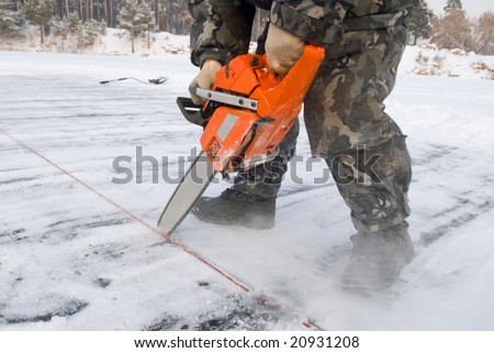 Worker carving out ice on lake