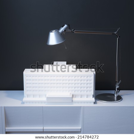 Model Of Building Under The Lamp On The Desk In Minimalist Interior