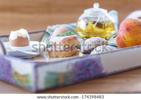 breakfast with a boiled egg, tea, sandwiches and fruit