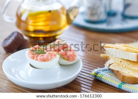 stuffed eggs with a sandwich and tea on a tray