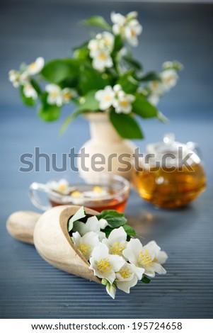 jasmine tea in a teapot with a branch of jasmine on a wooden table