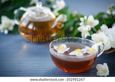 jasmine tea in a teapot with a branch of jasmine on a wooden table