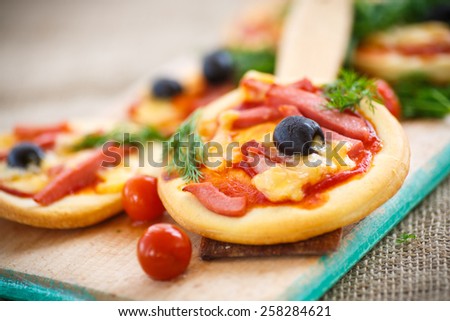 mini pizza with olives, bacon and cheese