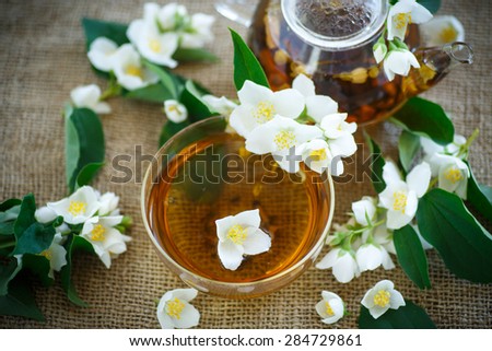 jasmine tea in a teapot with a branch of jasmine on the table