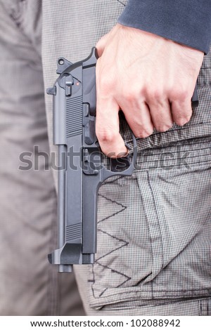 Man with gun, casual clothes, focus on the gun