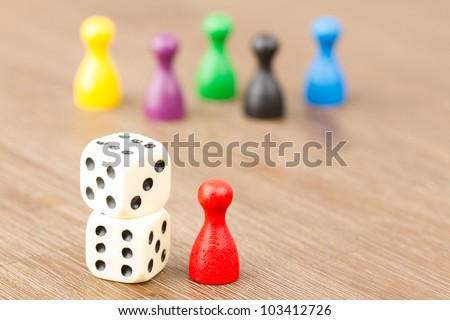 Six colored pawns and two dice isolated on a wooden background
