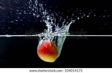 Red apple with splashing water on a black background, movement picture
