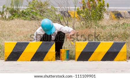 Man painting roadworks barriers on a road in Vietnam, Highway 1