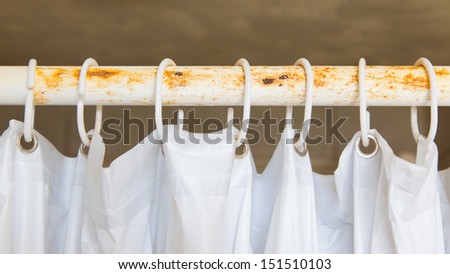 White shower curtain in the bathroom, hanging on a rusted bar