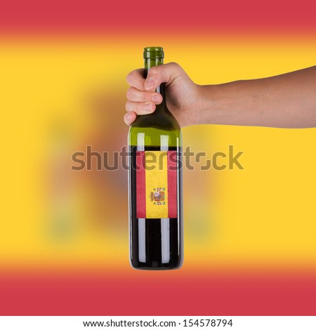 Hand holding a bottle of red wine, label of Spain, isolated on white
