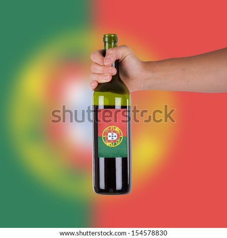 Hand holding a bottle of red wine, label of Portugal, isolated on white