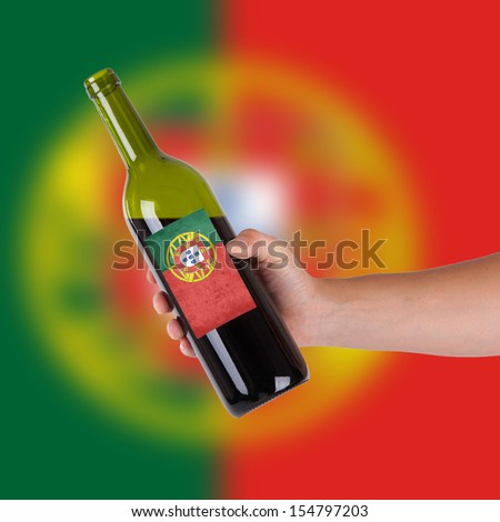 Hand holding a bottle of red wine, label of Portugal, isolated on white