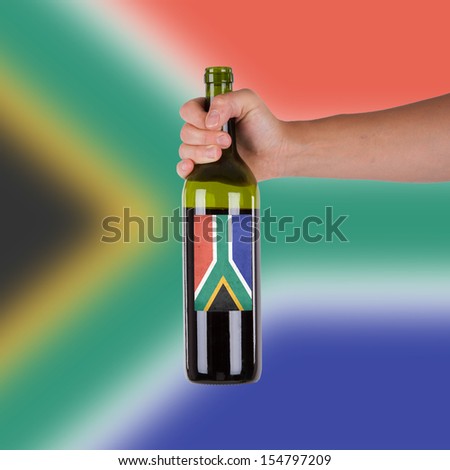 Hand holding a bottle of red wine, label of South Africa, isolated on white