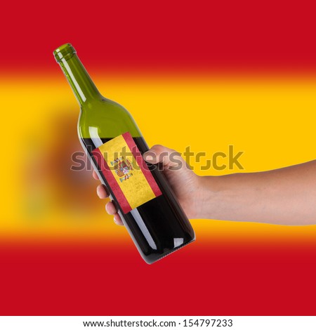 Hand holding a bottle of red wine, label of Spain, isolated on white