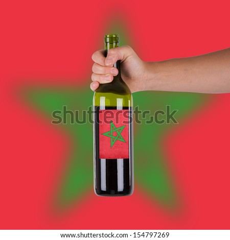Hand holding a bottle of red wine, label of Morocco, isolated on white
