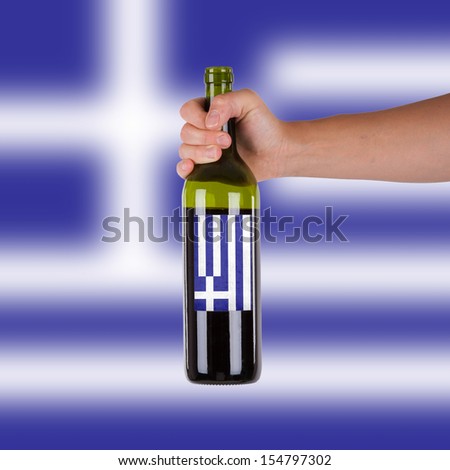 Hand holding a bottle of red wine, label of Greece, isolated on white,