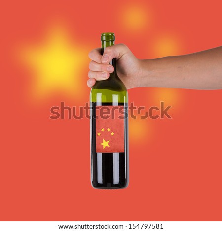 Hand holding a bottle of red wine, label of China, isolated on white,