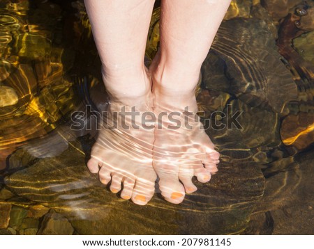 Dipping feet in water off a stone beach on a hot summer day