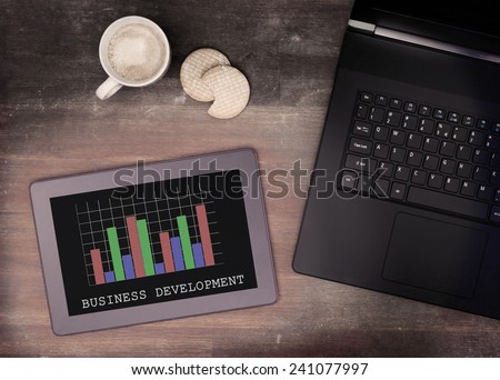 Tablet touch computer gadget on wooden table, graph, vintage look