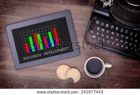 Tablet touch computer gadget on wooden table, graph, vintage look