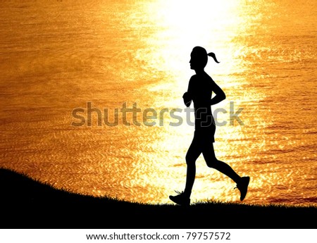 silhouetted healthy woman running at beach during sunset