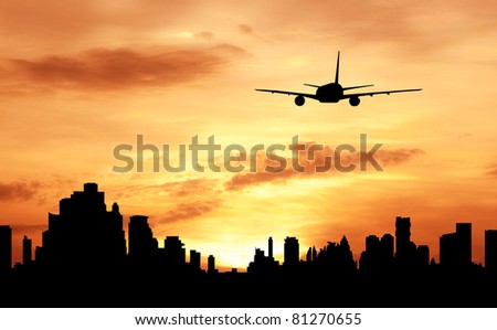 silhouette of commercial plane flying over a city during sunrise