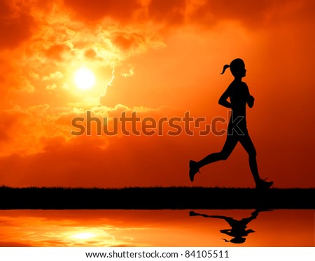 healthy woman running past the sun at sunset silhouetted