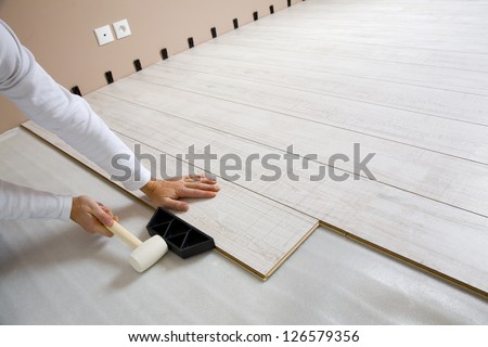 Worker laying a floor with laminated flooring boards
