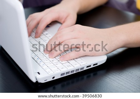 Male hands on a notebook keyboard (shallow DOF, focus on left hand)