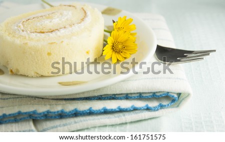The vanilla roll cake on the blue stripes clothes,yellow small flower on blue pale background
