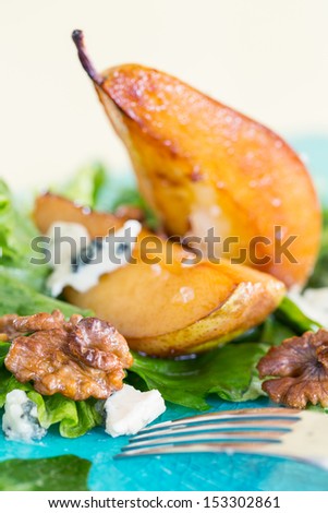 Salad with caramelized pears, blue cheese and walnuts on blue plate