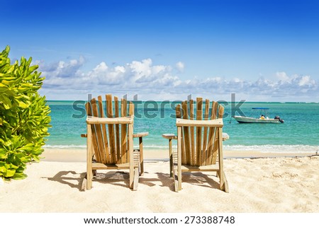 Two beach chairs on tropical shore, horizontal composition