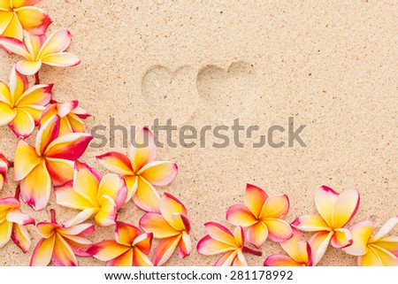 Two heart print on sand with frangipani flowers, top view, horizontal composition